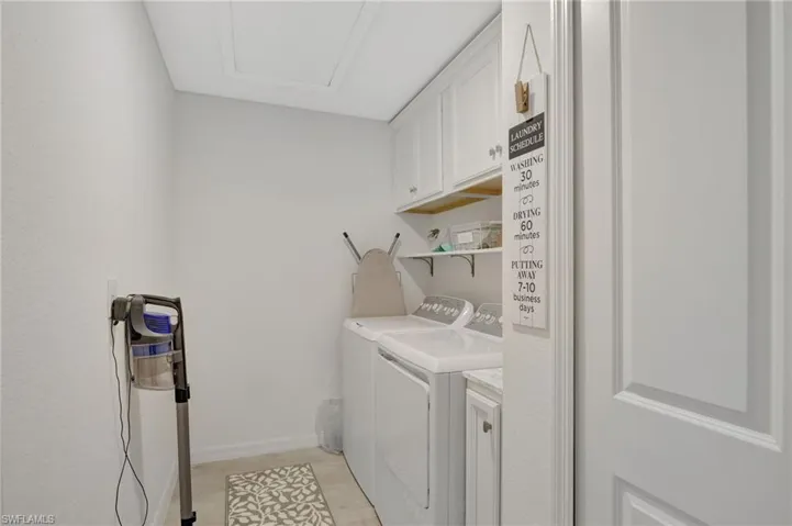 Washroom featuring washing machine and clothes dryer, cabinet space, baseboards, and light wood-style floors