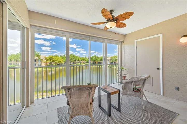 Sunroom / solarium with a textured wall, a water view, and ceiling fan