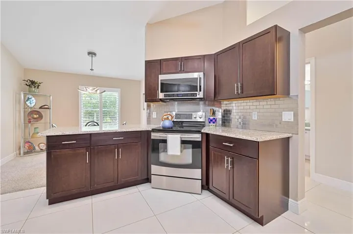Kitchen featuring dark brown cabinetry, stainless steel appliances, a peninsula, and decorative backsplash