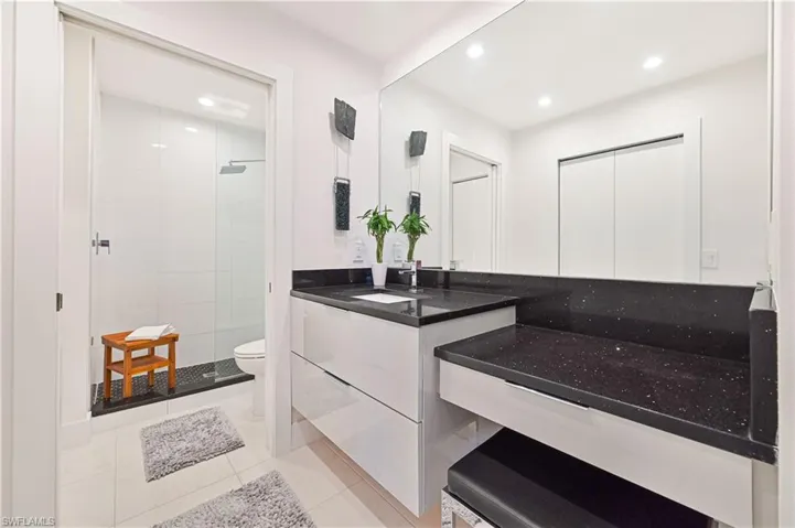 Bathroom with recessed lighting, toilet, vanity, and a stall shower