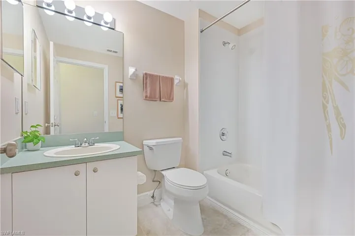 Bathroom featuring tile patterned floors, vanity, toilet, visible vents, and shower / bath combination with curtain
