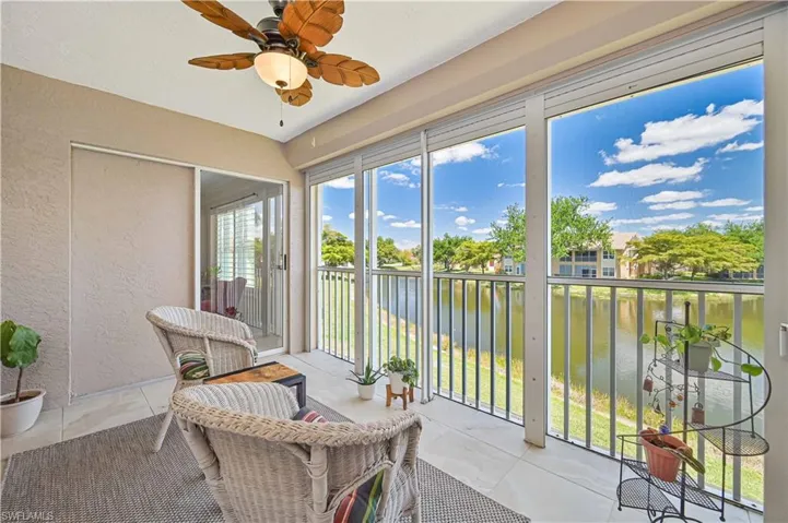 Sunroom featuring a textured wall, a water view, tile patterned flooring, and ceiling fan