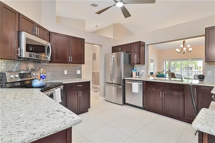 Kitchen featuring stainless steel appliances, a sink, dark brown cabinets, visible vents, and decorative backsplash