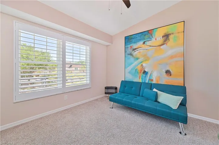 Sitting room with lofted ceiling, a healthy amount of sunlight, and carpet flooring