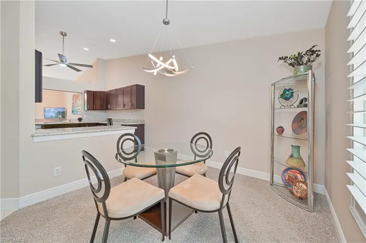 Dining space with light carpet, vaulted ceiling, baseboards, recessed lighting, and ceiling fan with notable chandelier