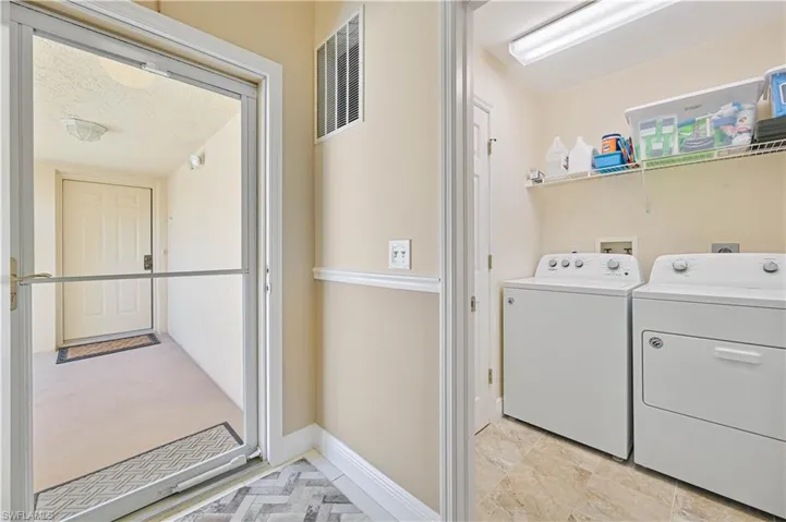 Clothes washing area with washing machine and dryer, baseboards, visible vents, and laundry area