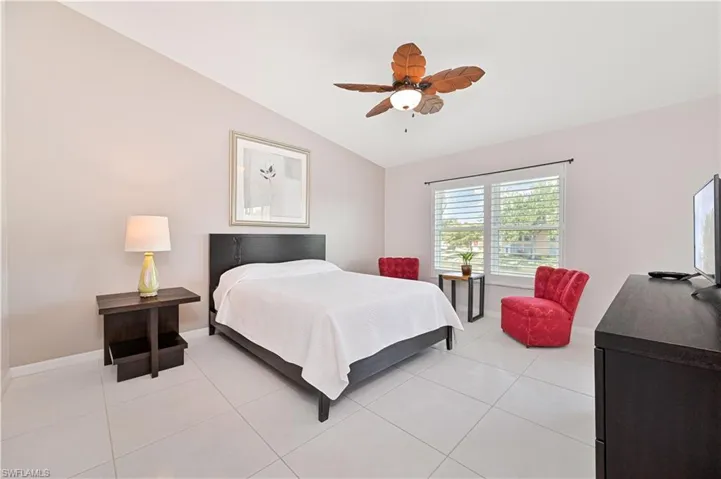 Bedroom featuring baseboards, lofted ceiling, ceiling fan, and light tile patterned floors