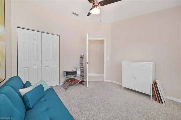 Living area with baseboards, a ceiling fan, visible vents, and carpet