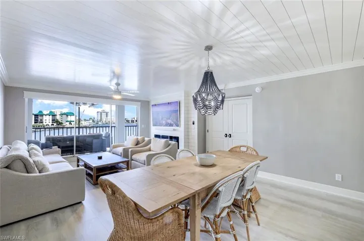 Dining area with ornamental molding, light wood-type flooring, a large fireplace, and a water view