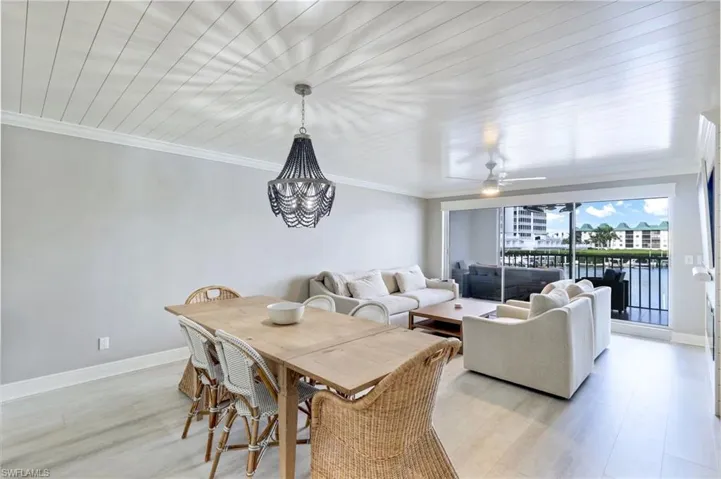 Dining room featuring crown molding, light wood-style flooring, ceiling fan, a water view, and a chandelier