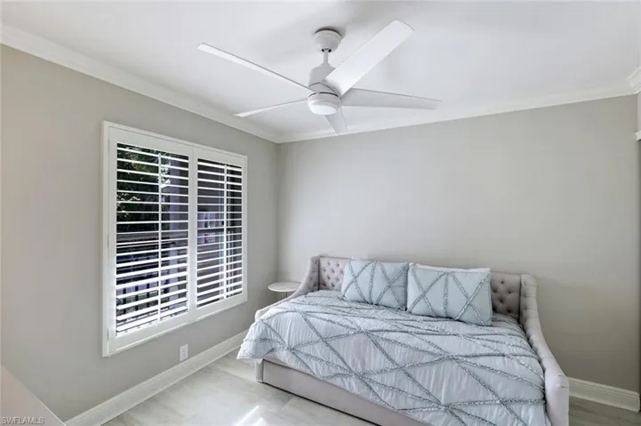Bedroom with ornamental molding, wood finished floors, and a ceiling fan