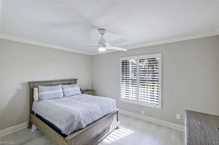 Bedroom with ornamental molding, a ceiling fan, and light wood-type flooring