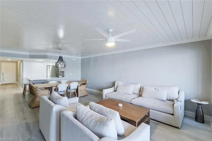 Living area featuring wood finished floors, ornamental molding, a ceiling fan, and wood ceiling