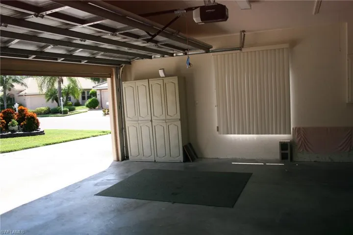 Spacious garage featuring a concrete floor, built-in cabinetry, and window with vertical blinds