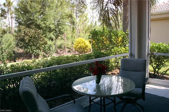 Screened lanai featuring a privacy screen, outdoor carpeting, and mature landscaping