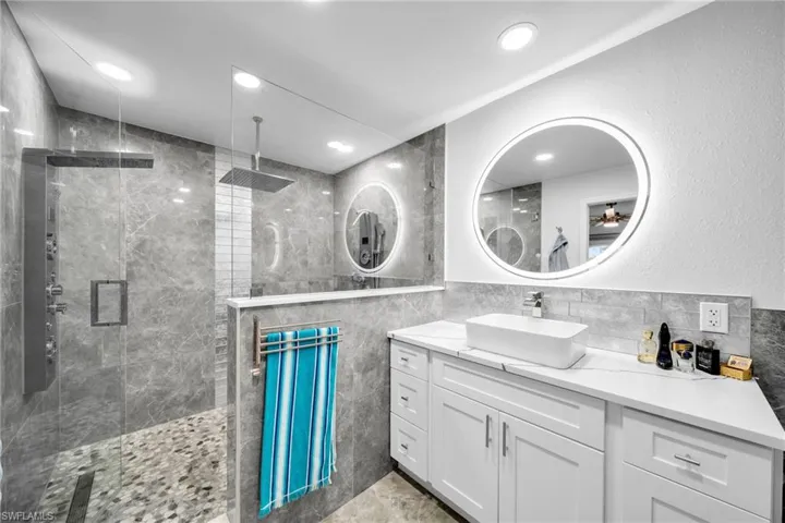 Bathroom with vanity, tasteful backsplash, tile walls, and a shower with shower door