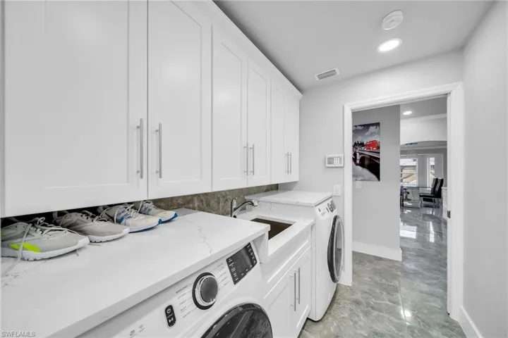 Laundry area featuring independent washer and dryer, cabinets, and sink