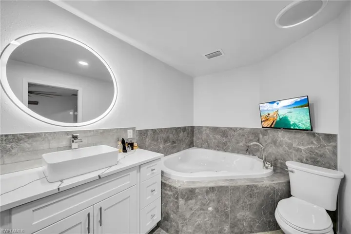 Bathroom with vanity, toilet, and a relaxing tiled tub
