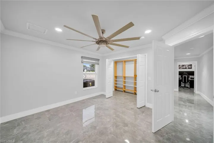 Unfurnished bedroom featuring crown molding, ceiling fan, and a closet