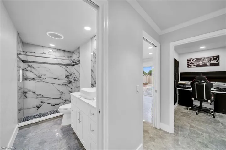 Bathroom featuring toilet, a tile shower, crown molding, and vanity