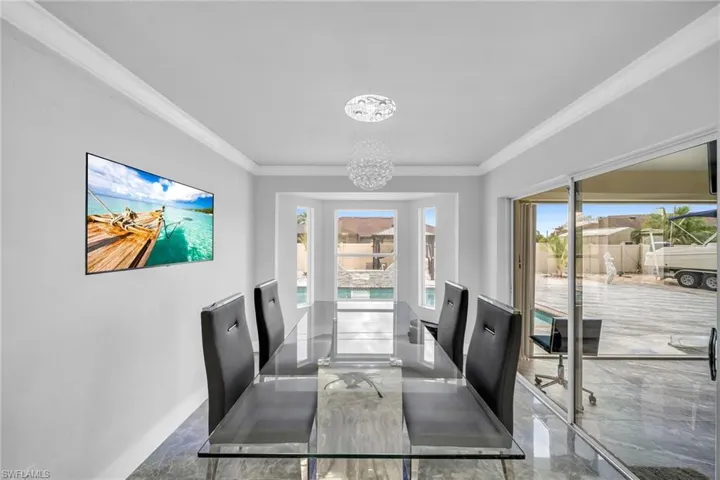 Dining area featuring ornamental molding, a chandelier, and a healthy amount of sunlight