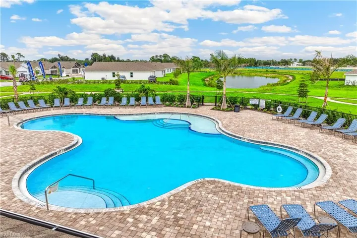 The property features an outdoor swimming pool with a paved patio surround, lounge chairs, and palm trees