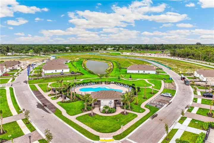 Aerial view of the community, featuring a central swimming pool with surrounding lounge chairs, a covered outdoor area, and established landscaping