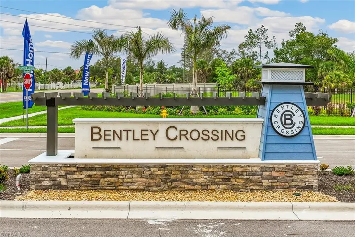 Entrance sign for Bentley Crossing, featuring a stacked stone base, a white sign with raised lettering, and a blue decorative element with a circular emblem