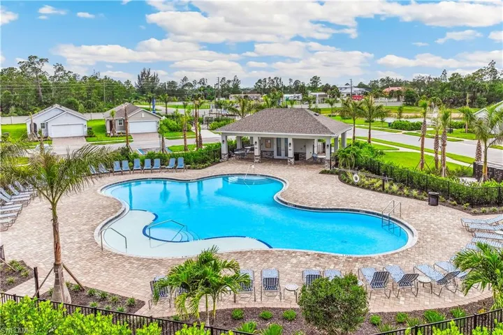 Inviting outdoor pool area featuring a freeform pool, surrounding paver decking, and a covered cabana