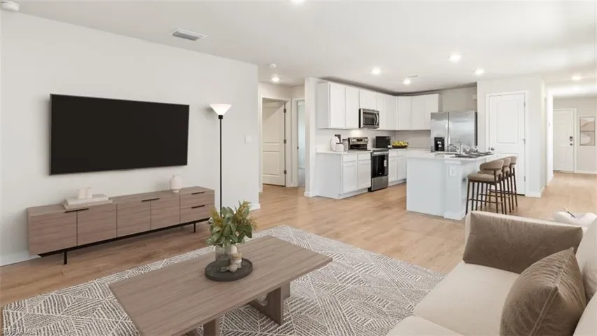 This image is virtually staged. Living room featuring light wood-style floors and recessed lighting