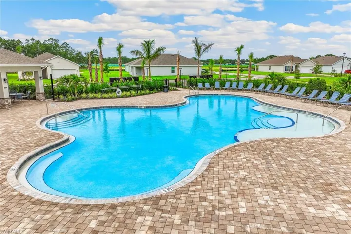 The property features a large, irregularly shaped swimming pool with integrated steps, surrounded by a paved patio area