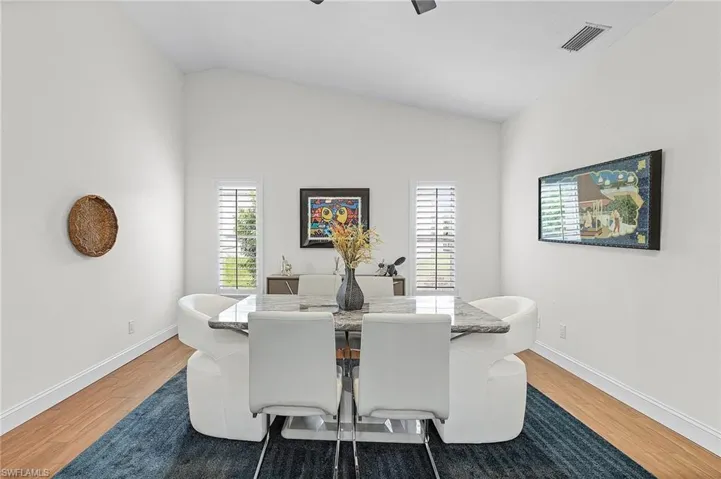 Dining area featuring vaulted ceiling, light wood-type flooring, and a ceiling fan
