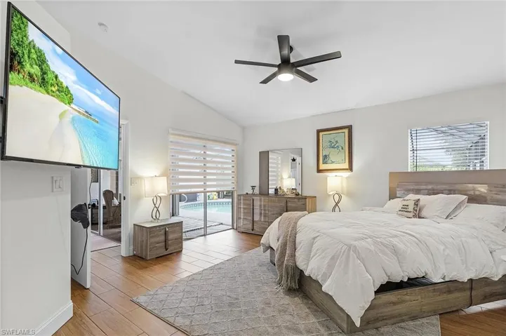 Bedroom featuring access to outside, multiple windows, ceiling fan, vaulted ceiling, and light wood-style flooring