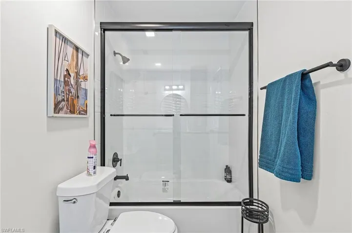 Bathroom with combined bath / shower with glass door and toilet