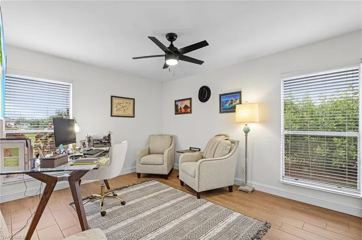Office area with light wood finished floors, a ceiling fan, and plenty of natural light