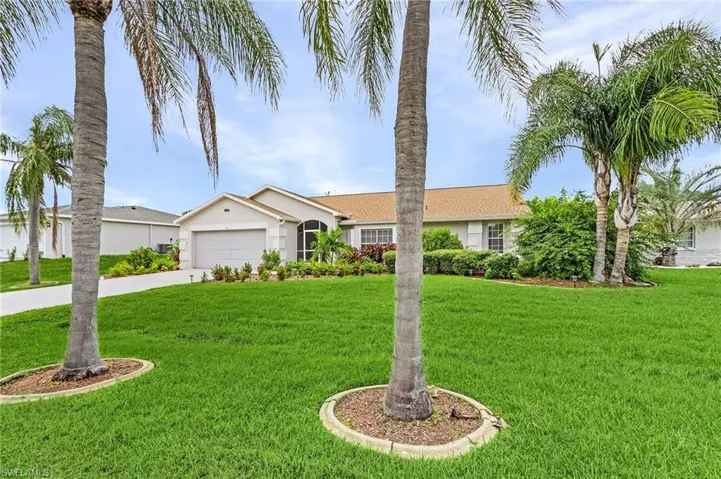 Ranch-style home with a front lawn, stucco siding, a garage, and concrete driveway