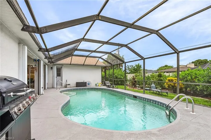 Swimming pool with area for grilling, glass enclosure, a sunroom, and a patio area