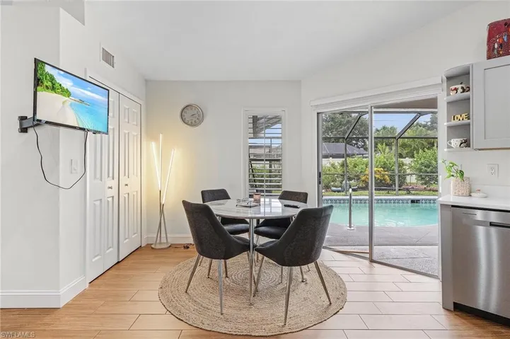 Dining space featuring a sunroom, light wood-type flooring, and vaulted ceiling