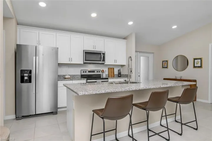 Kitchen with white cabinets, an island with sink, and stainless steel appliances