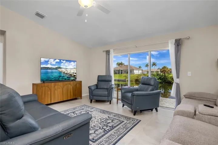 Tiled living room featuring ceiling fan and vaulted ceiling