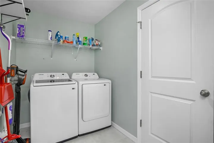 Clothes washing area with independent washer and dryer and light tile patterned floors