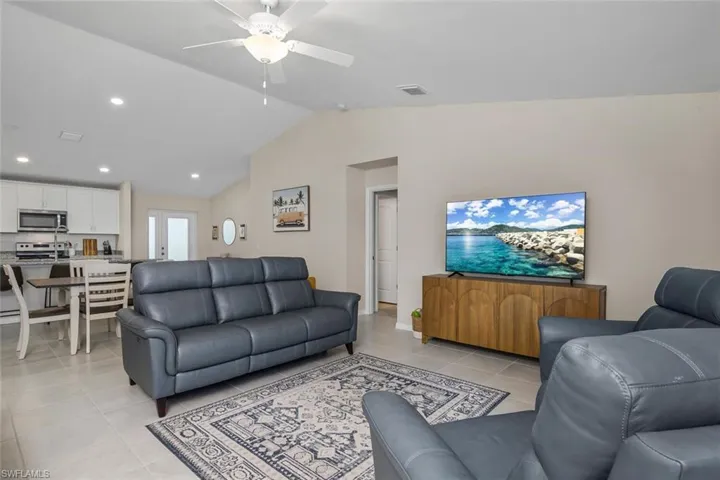 Tiled living room featuring lofted ceiling and ceiling fan