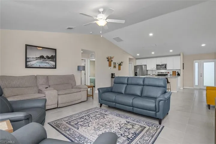 Tiled living room with ceiling fan and vaulted ceiling