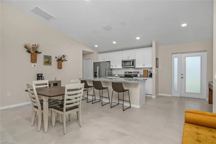 Kitchen featuring appliances with stainless steel finishes, a breakfast bar area, white cabinets, a kitchen island with sink, and light tile patterned flooring