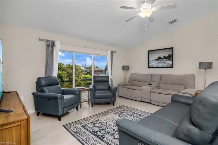 Living room with ceiling fan, lofted ceiling, and light tile patterned floors