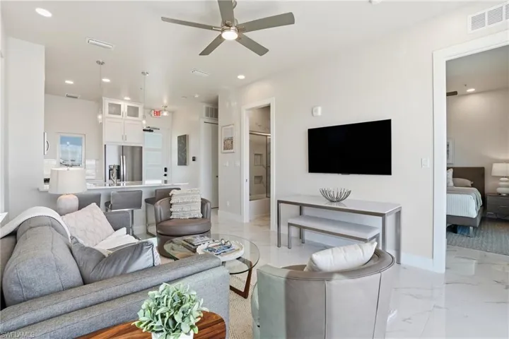 Living area featuring light marble finish floors, a ceiling fan, and recessed lighting - Virtually Edited Image
