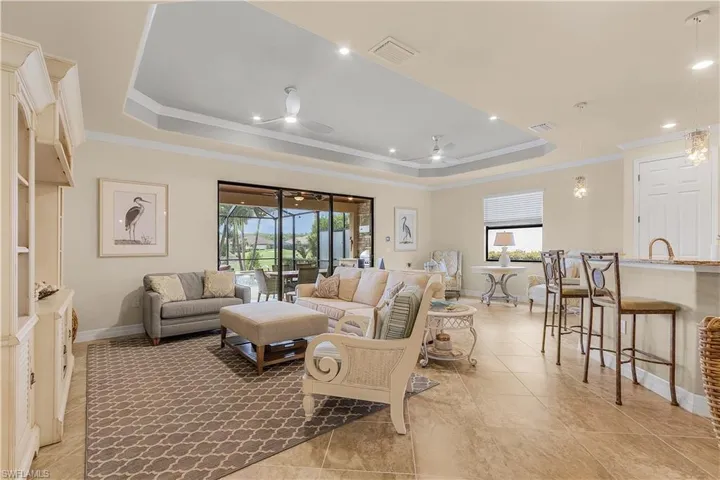 Living room featuring crown molding, a tray ceiling, and light tile patterned floors