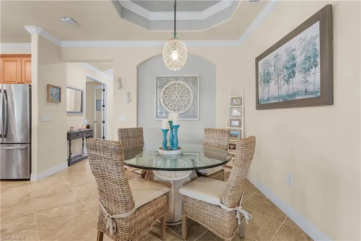 Tiled dining area featuring ornamental molding and a tray ceiling
