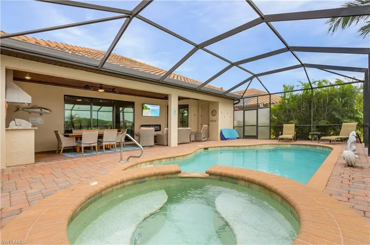 View of swimming pool with an in ground hot tub, ceiling fan, a patio area, and a lanai