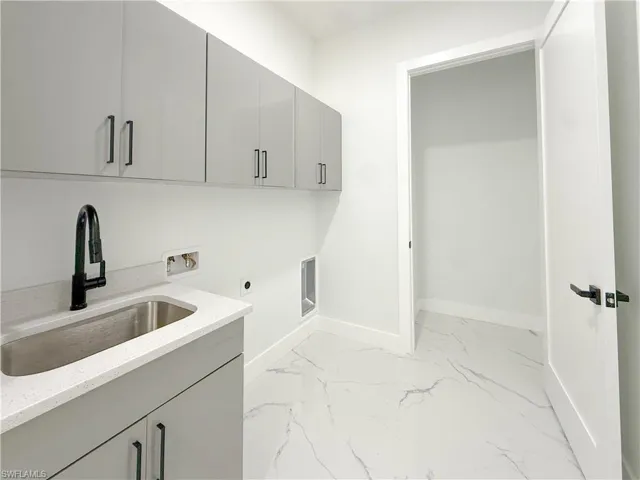 Laundry area featuring hookup for a washing machine, light marble finish floors, electric dryer hookup, and cabinet space